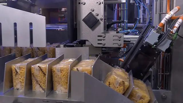 Several packets of pasta in a plastic package are conveyed through a packaging machine.