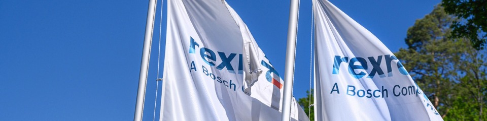 Two flags with the Bosch Rexroth logo in front of a Bosch Rexroth building in Lohr.