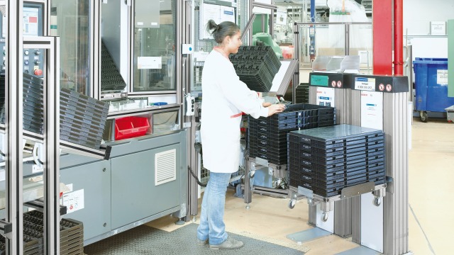 Empleado trabajando con elevadores de cajas eléctricos en el puesto de trabajo de Bosch Rexroth